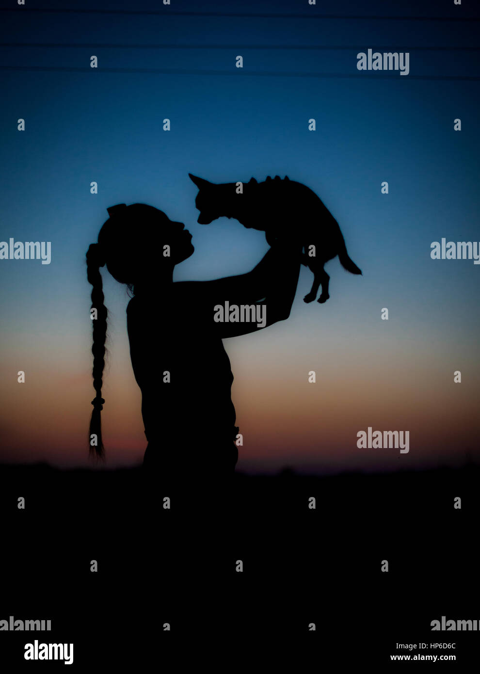 Silhouette of young girl and her little dog on sunset. Beautiful sky