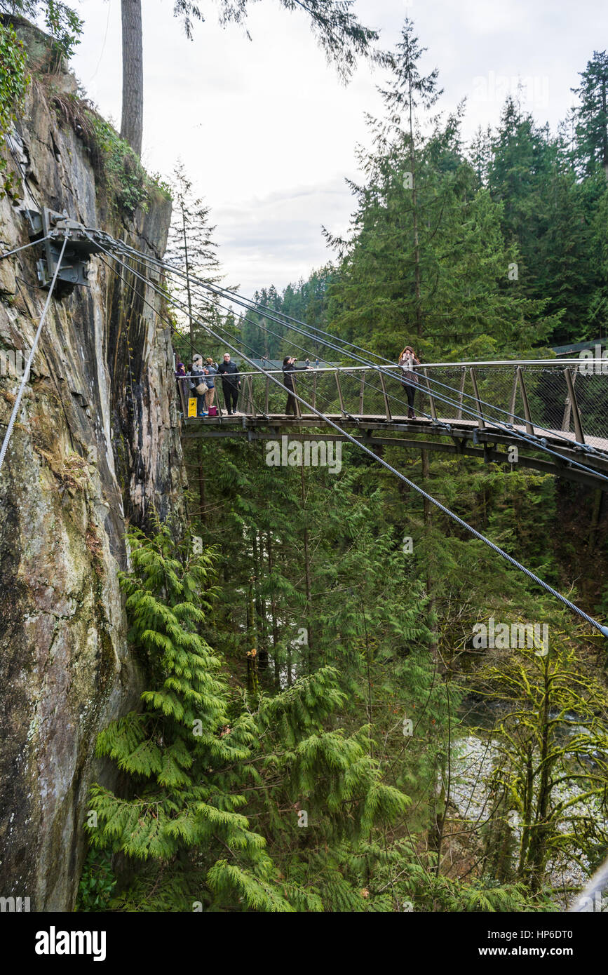 Vancouver, Canada - January 28, 2017: A suspension bridge hanging from a cliff face high above the canyon at the Capilano Suspension Bridge Park Stock Photo
