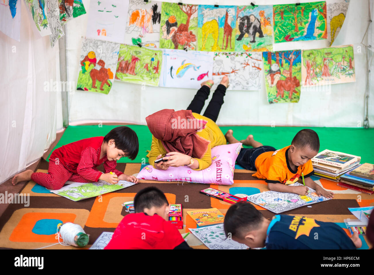 Jakarta, Indonesia: Preschool children drawing nature conservation-themed images by coloured pencils on papers at a stand, during a Greenpeace event. Stock Photo