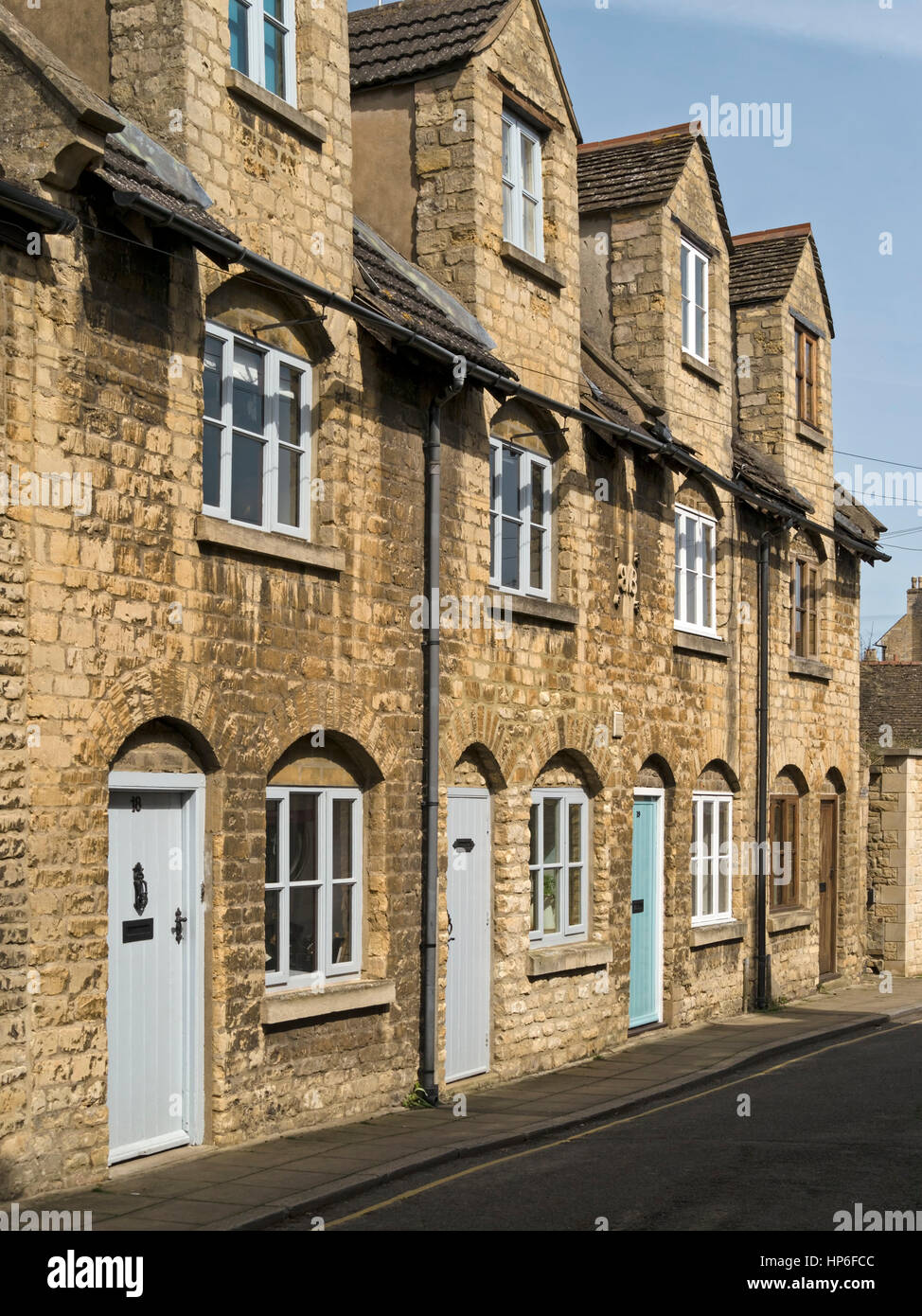 Row of old stone terraced cottages with arch window and front door features, Austin Street, Stamford, Lincolnshire, England, UK. Stock Photo