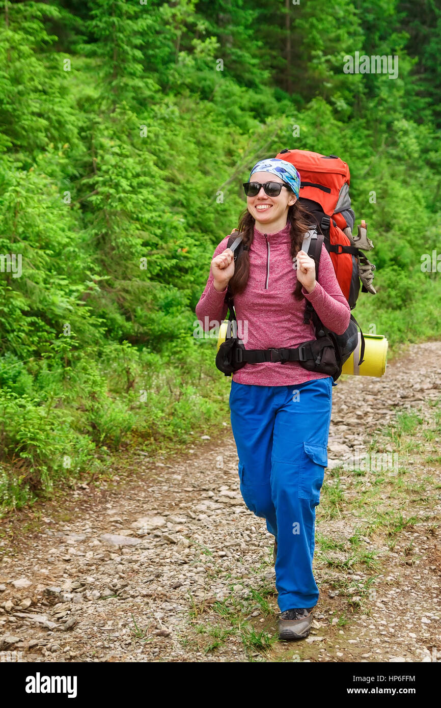 happy woman hiker trekking on trail in mountains. Girl hiker