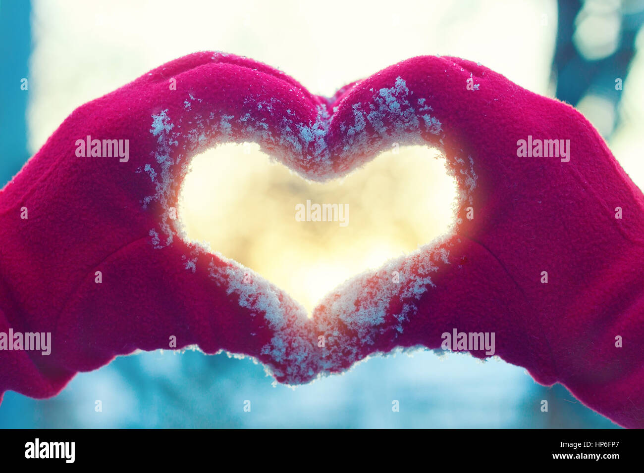 Woman hands in winter gloves heart symbol shaped lifestyle and feelings concept with sunset light winter nature on background Stock Photo