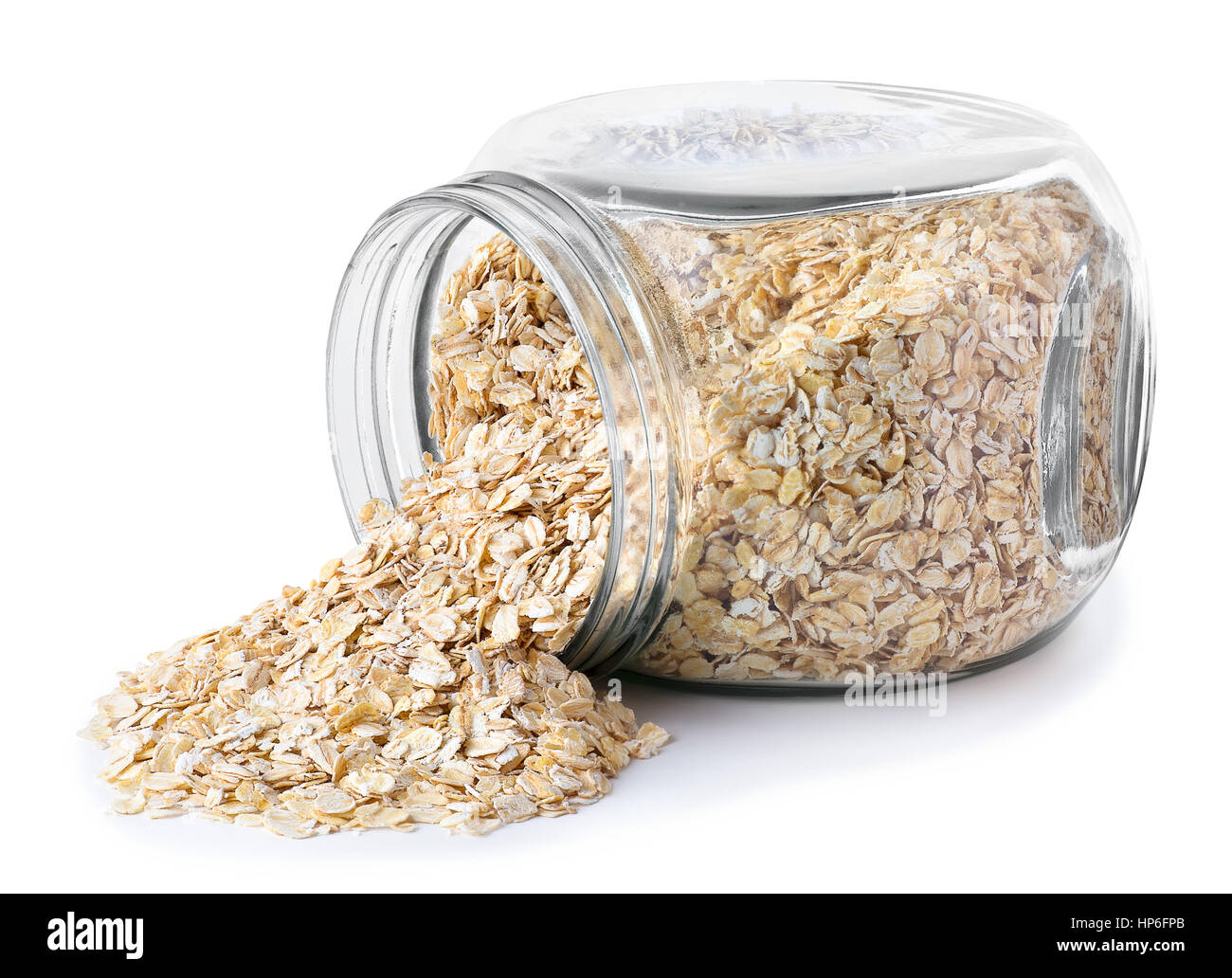 transparent glass jar with rolled oats isolated on white background. Glass jar with oatmeal flakes lying on side isolated on white background. Scatter Stock Photo