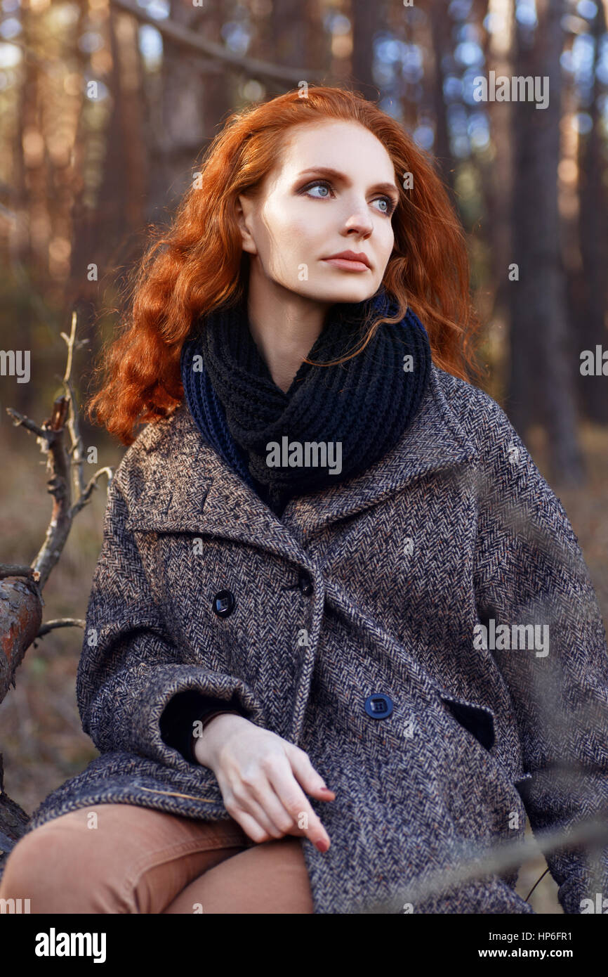 Beautiful red-haired woman. Redhead girl in autumn clothes outdoors. Redhead woman outdoor in autumn park, weared scarf and coat. Autumn fashion look Stock Photo