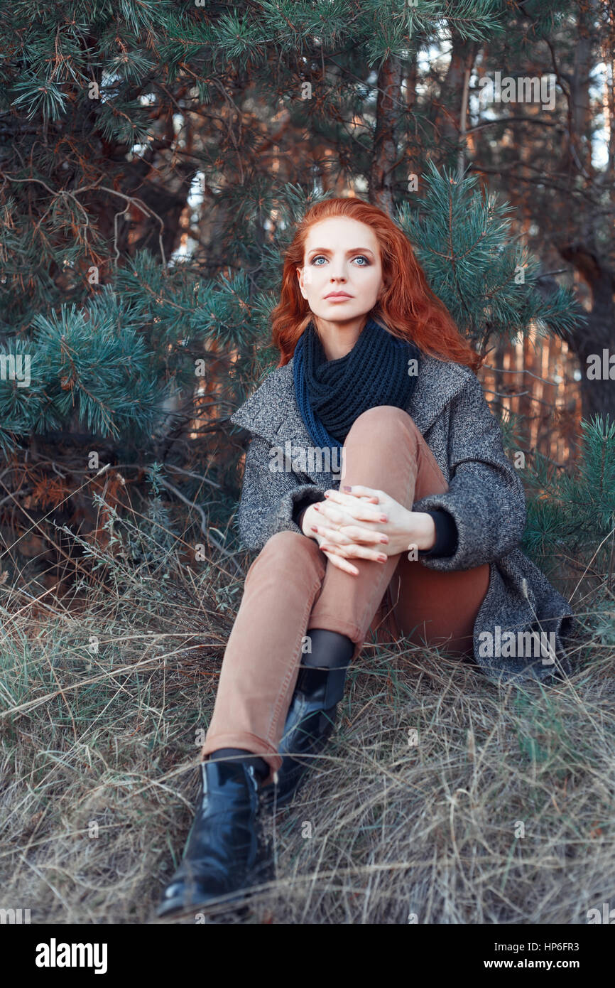 Beautiful red-haired woman. Redhead girl in autumn clothes in the forest. Redhead woman outdoor in autumn park, weared scarf and coat. Autumn fashion  Stock Photo