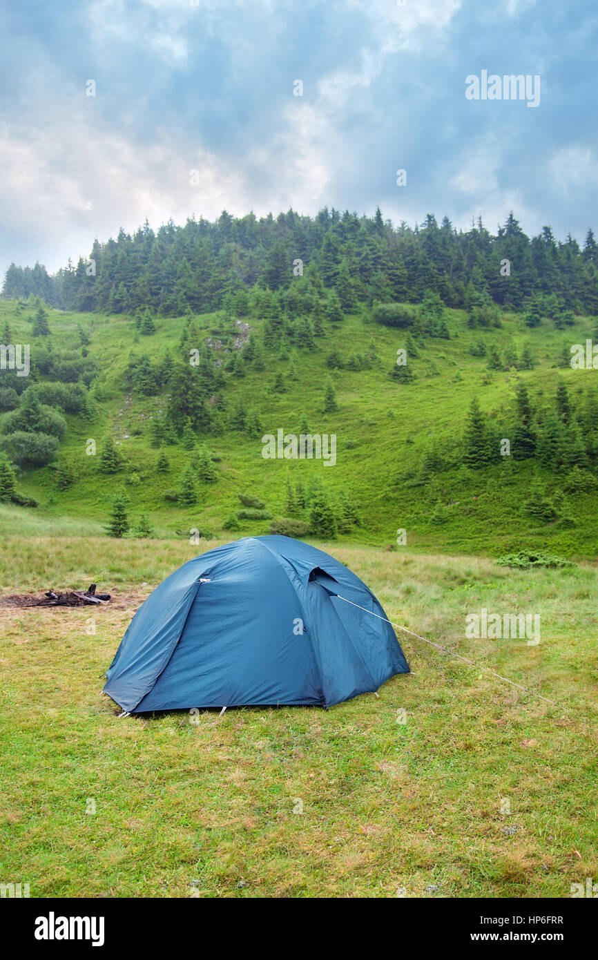 Tourist tent. Camping. Tourist tent on meadow green pine forest, mountains and sky on the background. Adventure travel active lifestyle freedom outdoo Stock Photo