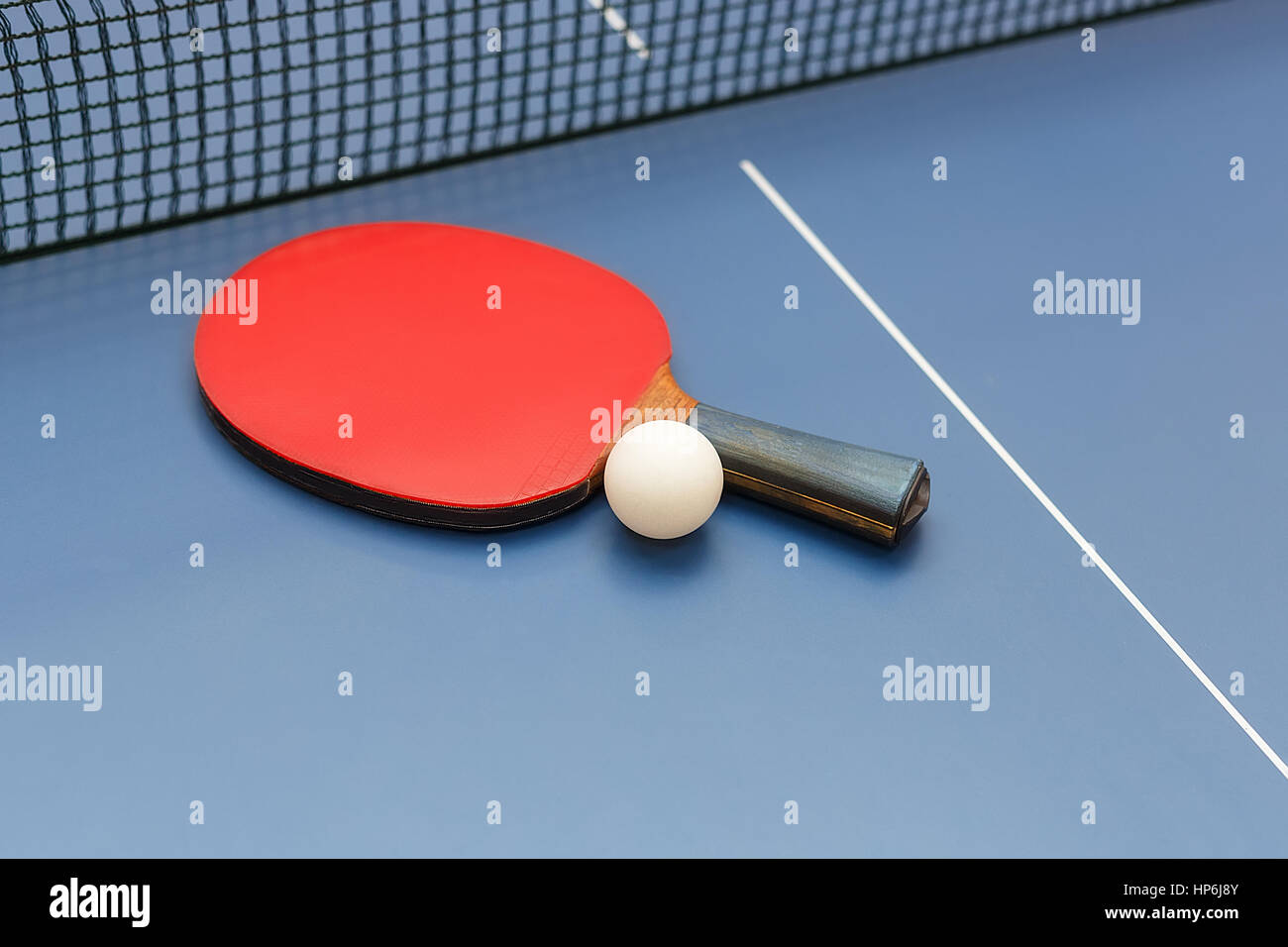 Table tennis racket, white ball and net on a on blue board. Equipment