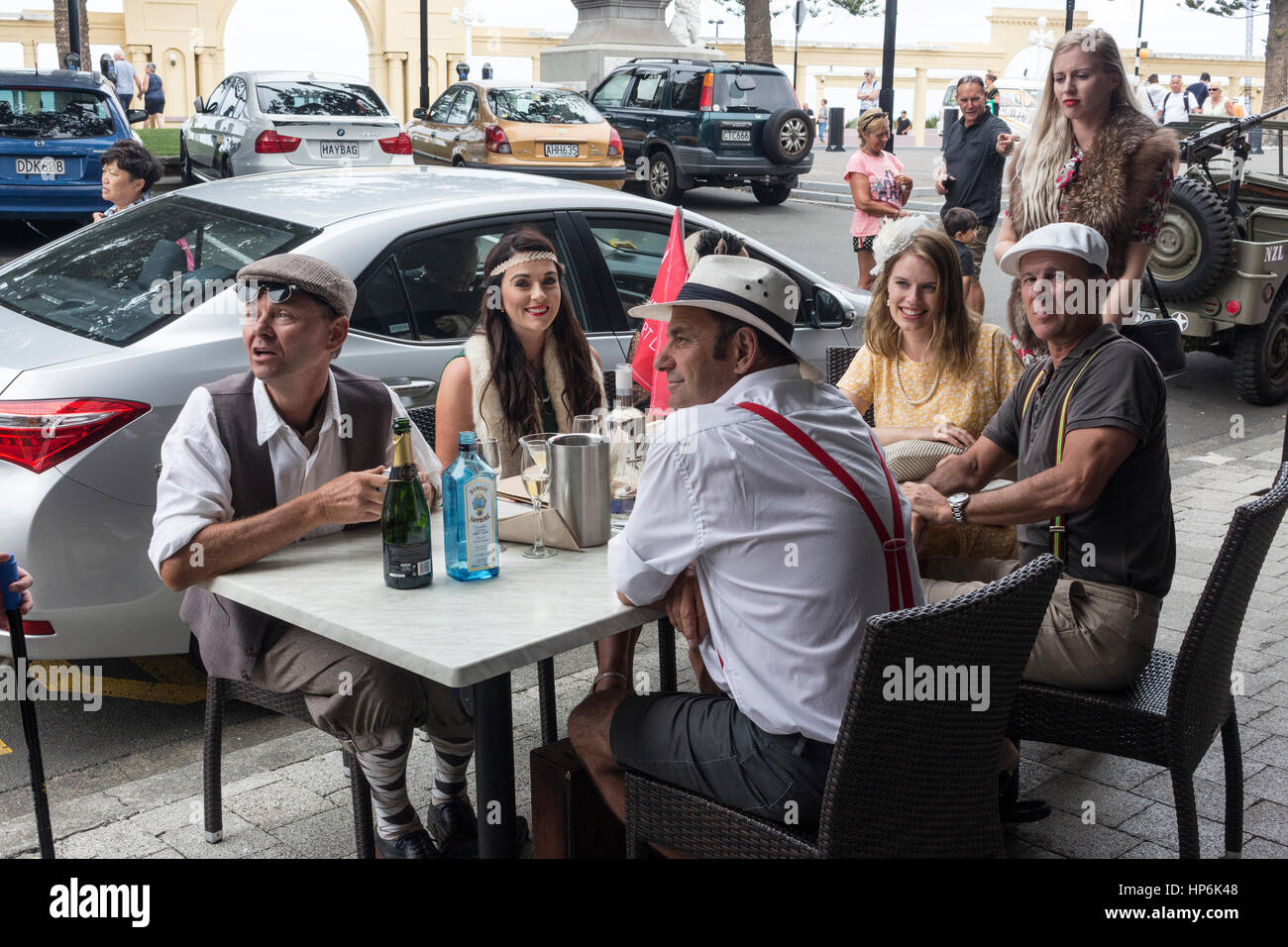 Nice people with fancy clothes sitting on a table outdoors celebrating in the Art Deco Festival 2017 in Napier, New Zealand Stock Photo