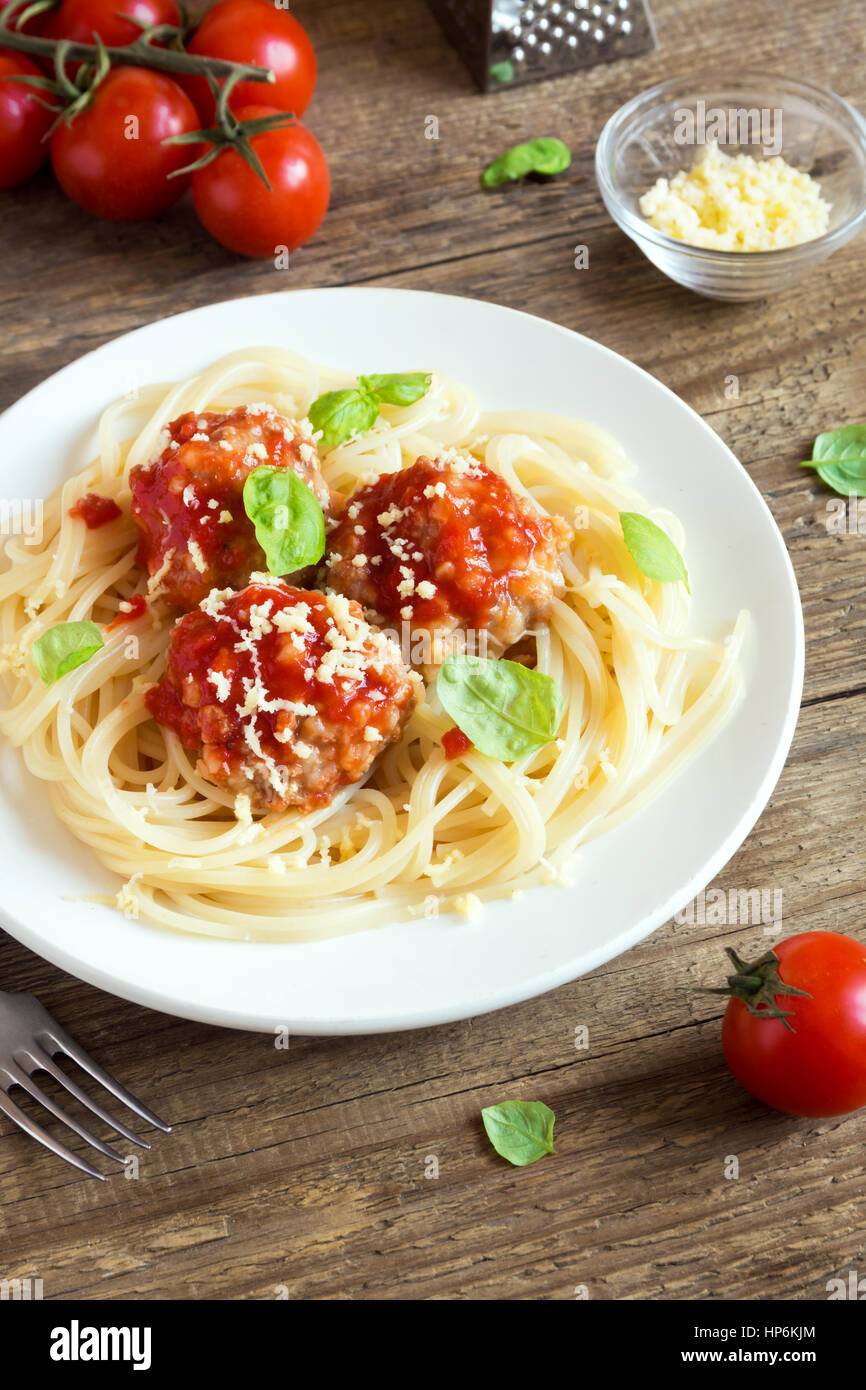 Spaghetti pasta with meatballs, tomato sauce, grated parmesan cheese and fresh basil - healthy homemade italian pasta on rustic wooden background with Stock Photo