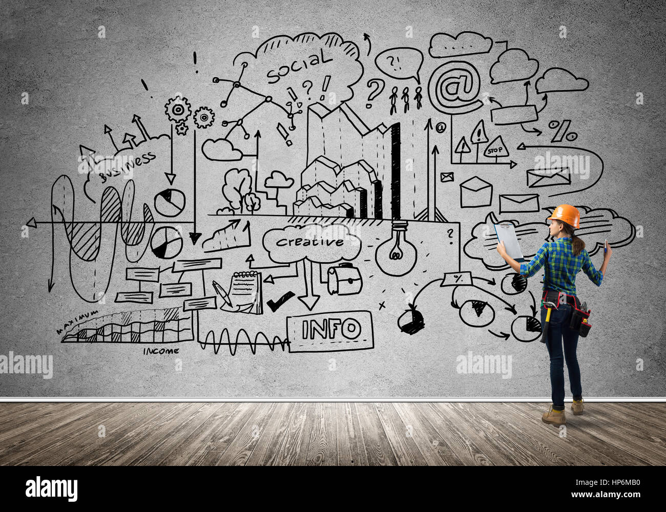 Back view of engineer woman in hardhat and sketched concept on wall ...