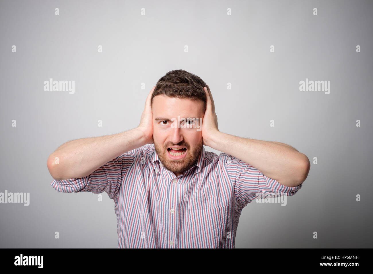 Man with hands on ears bothered annoyed Stock Photo