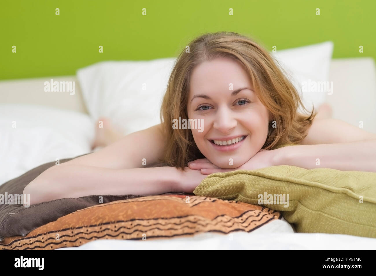Model released , Junge Frau, 25+, liegt mit Kissen auf dem Bett - woman with pillows lying on the bed Stock Photo