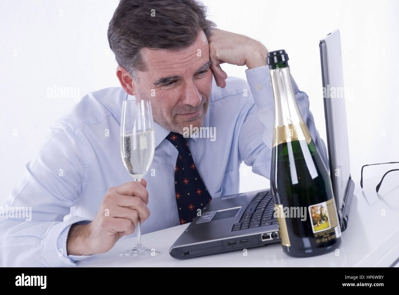 Model released , Geschaeftsmann mit Sekt bei der Arbeit - business man with alcohol at work Stock Photo