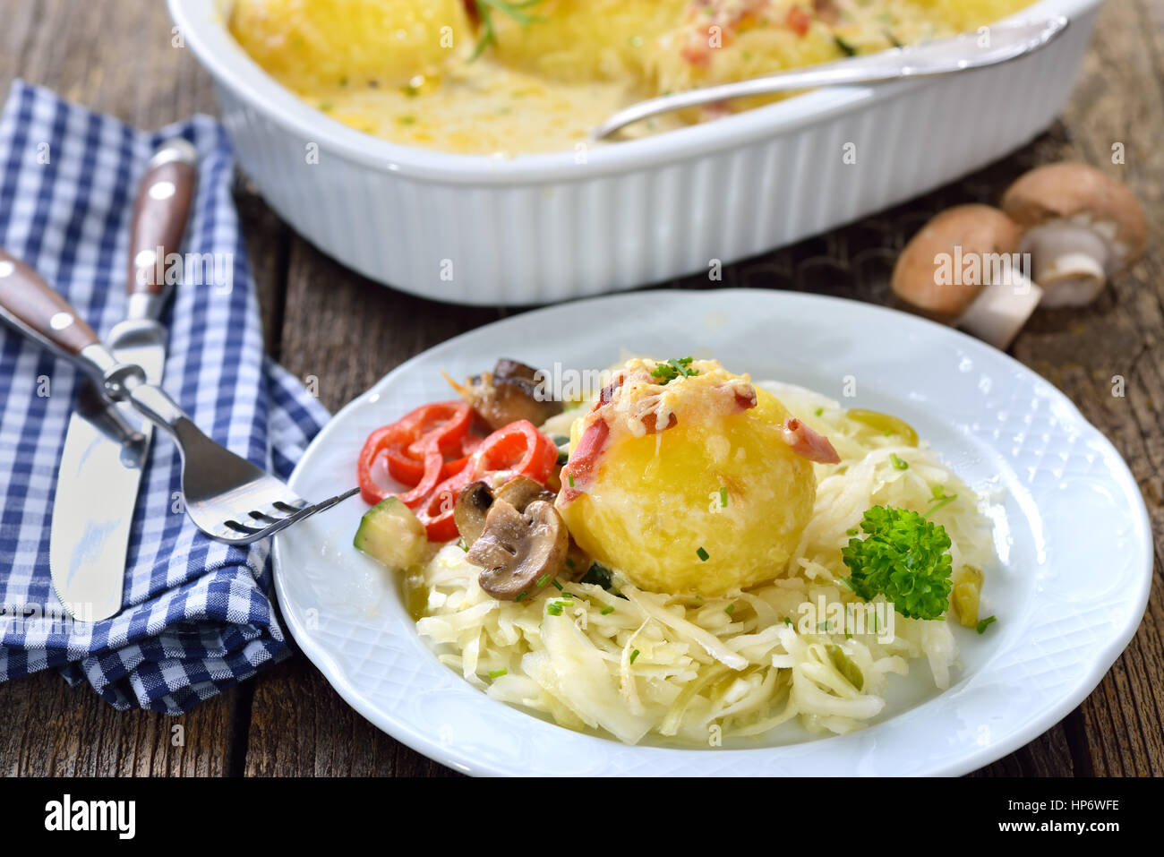 Hearty potato dumpling gratin with cheese and bacon served on warm coleslaw Stock Photo