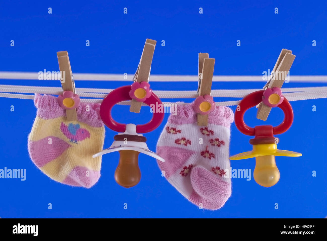 Schnuller und Babysocken haengen an Waescheleine - baby socks and dummies on clothesline Stock Photo