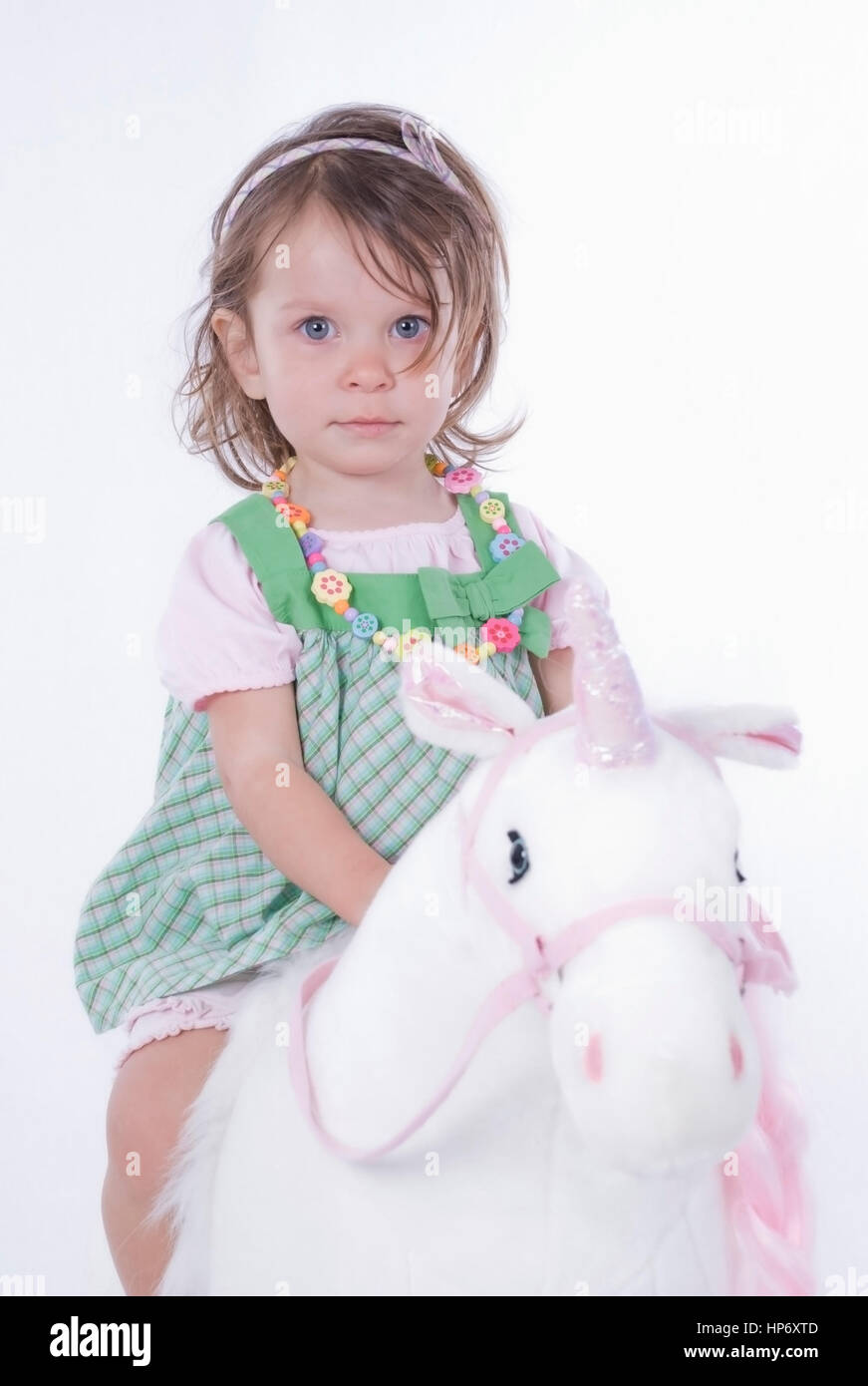 Model released , Kleines Maedchen, 2 Jahre, sitzt auf Stoffeinhorn - little  girl sitting on an unicorn toy Stock Photo - Alamy