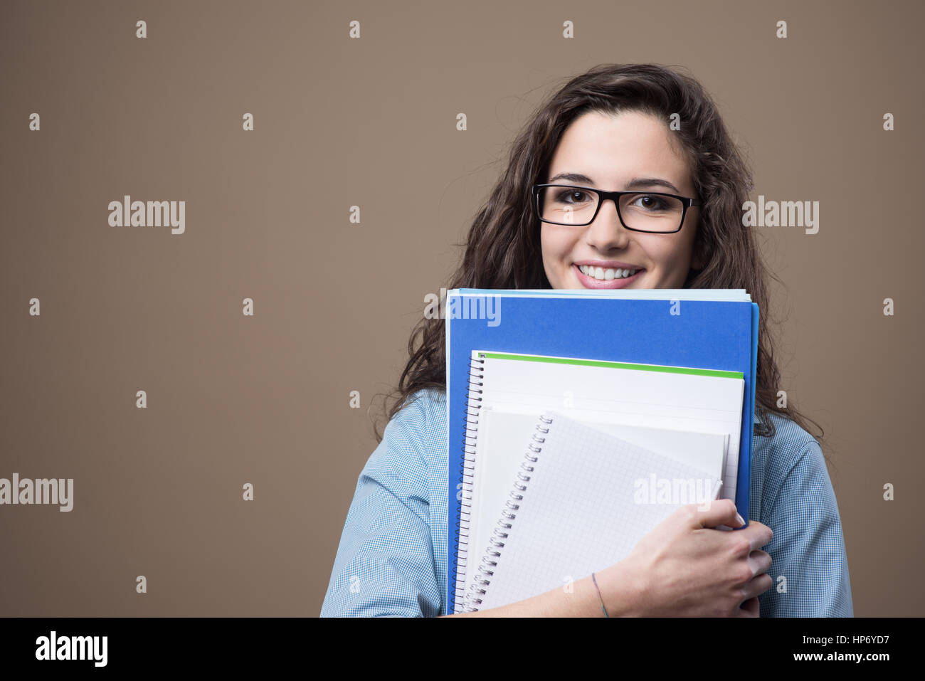Beautiful young teenager girl student posing with notebooks and smiling ...