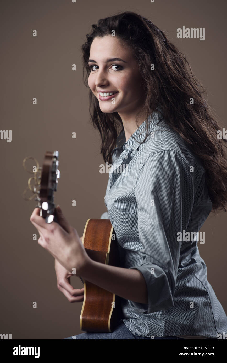 Beautiful young smiling girl playing acoustic guitar Stock Photo - Alamy