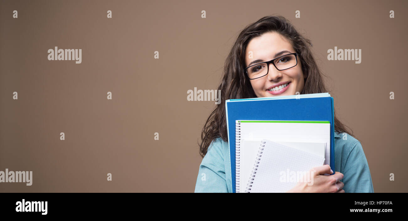 Beautiful young teenager girl student posing with notebooks and smiling ...