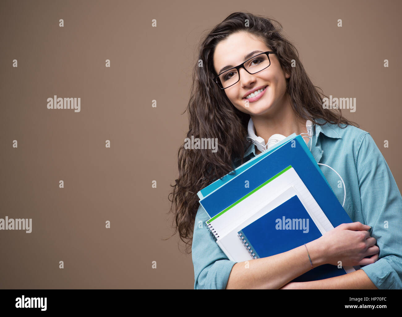 Beautiful young teenager girl student posing with notebooks and smiling ...