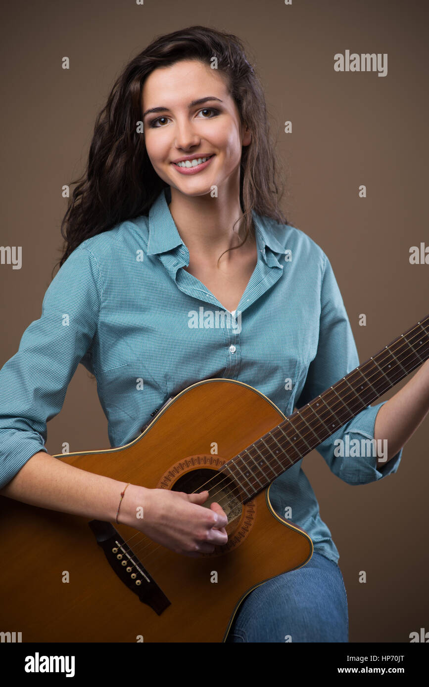 Beautiful young smiling girl playing acoustic guitar Stock Photo - Alamy