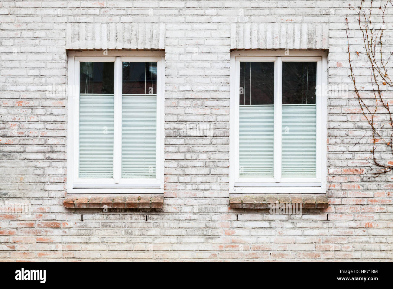 Gray brick wall with two windows closed with louvers, background texture Stock Photo