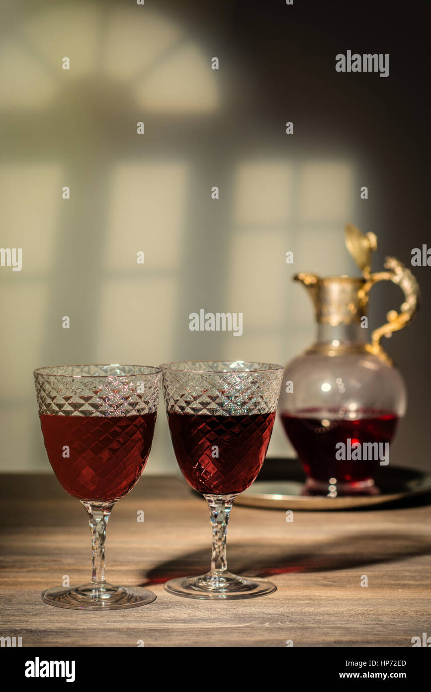 Two antique glasses filled with claret with decanter in the background Stock Photo