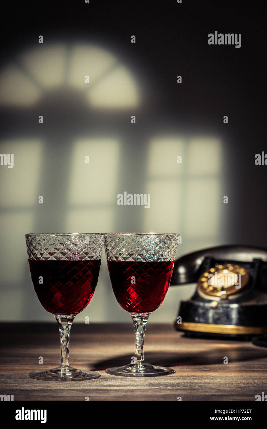 Two antique glasses filled with claret.  Vintage telephone in the background Stock Photo