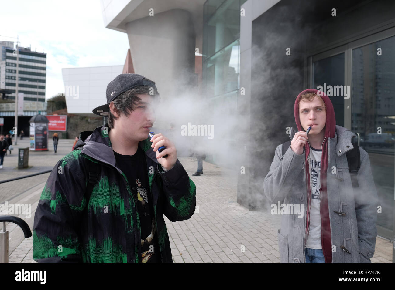 Carrie Edwards (left) 22 of age and Andrew Shaw (right) (22), USW Music Industry students, smoke e-cigarette during a break outside Atrium USW Stock Photo