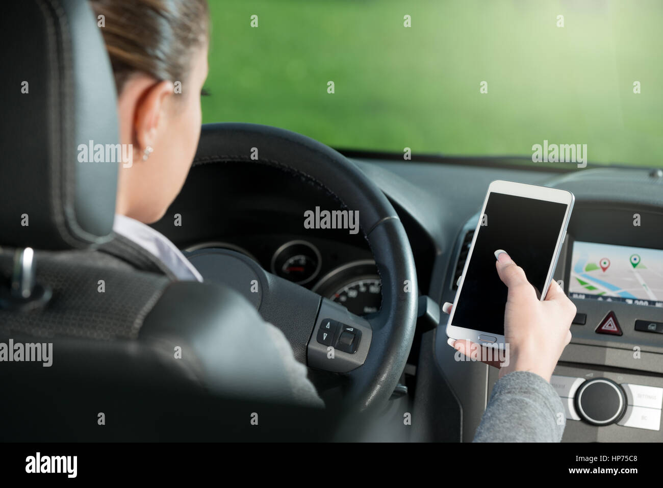 Young female driver using touch screen smartphone and gps navigation in