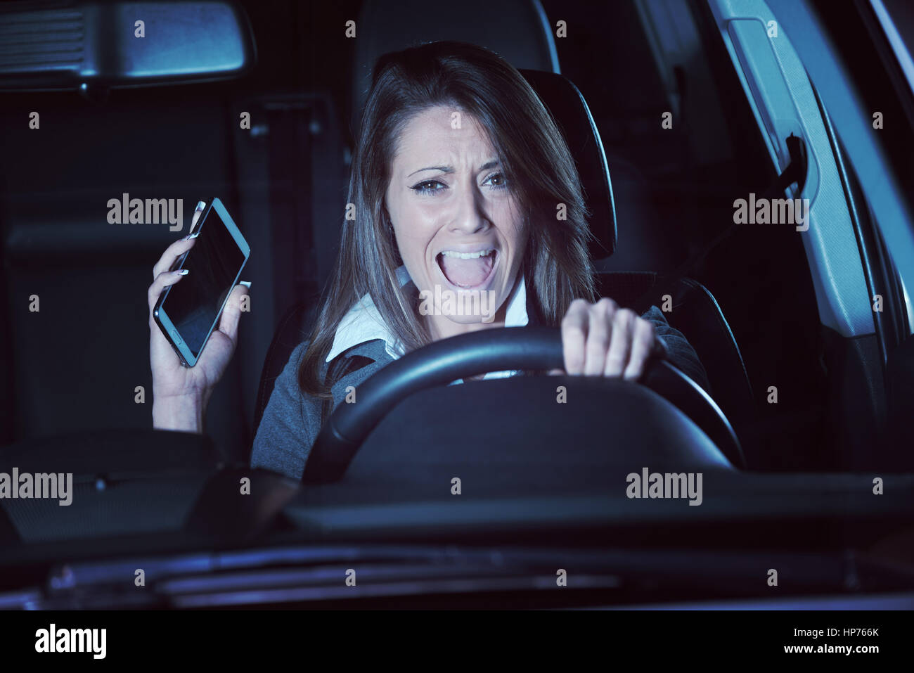 Young terrified woman driving and having a car accident at night Stock