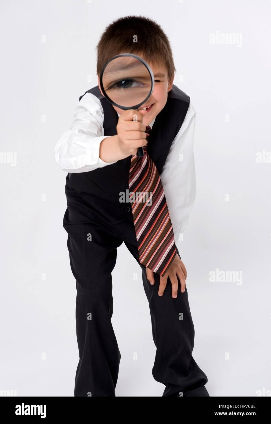 Model released, Junge, 8, im Businesslook mit Lupe - young businessman with loupe searching for something Stock Photo