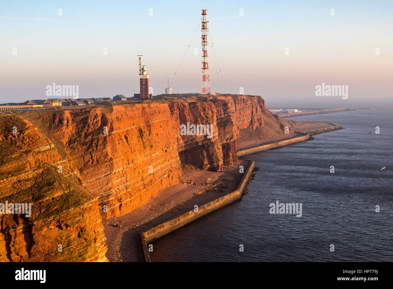 The red steep coast line of Helgoland, an German Island in the North Sea, lighthouse and radio-relay system antenna mast, Stock Photo