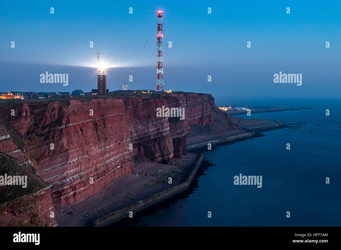 The red steep coast line of Helgoland, an German Island in the North Sea, lighthouse and radio-relay system antenna mast, Stock Photo
