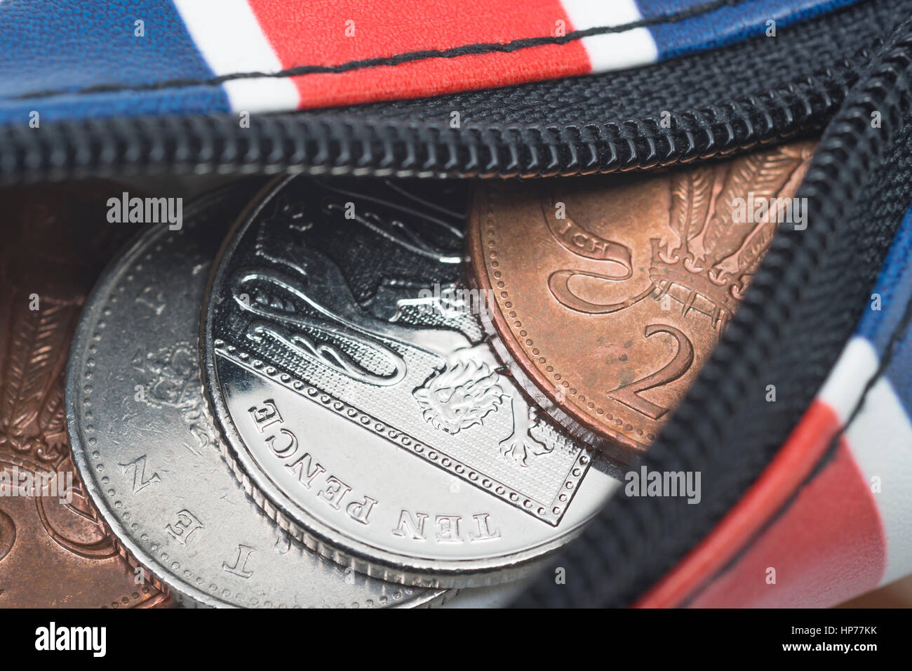 Zippered Union Jack coin purse with British coins / coinage spilling out. For household spending, the budget, rising prices, saving pennies, destitute Stock Photo