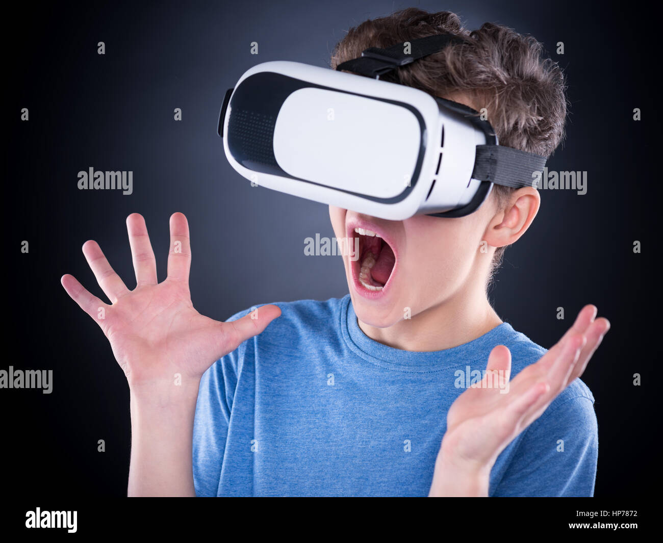 Amazed teen boy screaming, wearing virtual reality goggles watching movies or playing video games. Surprised teenager looking in VR glasses and shouti Stock Photo