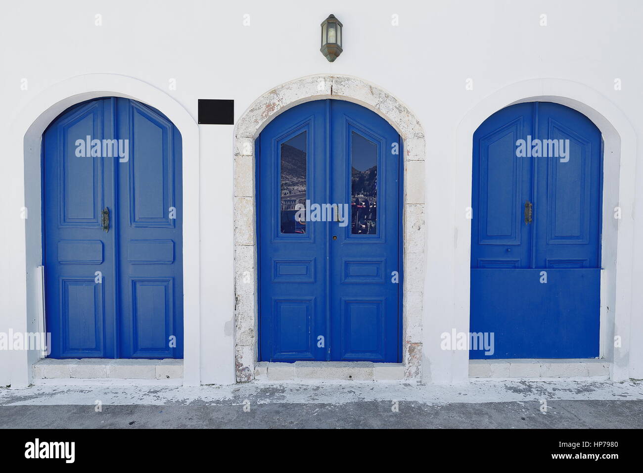 Three blue wooden doors on the whitewashed wall of a restored neoclassical house facing the waterfront of the main harbor in the center of town area.  Stock Photo