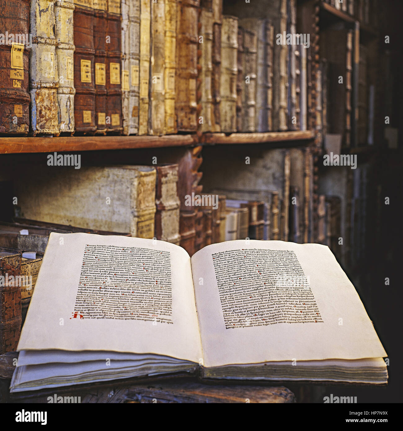 Altes, aufgeschlagenes Buch vor Regal mit alten Buechern Stock Photo