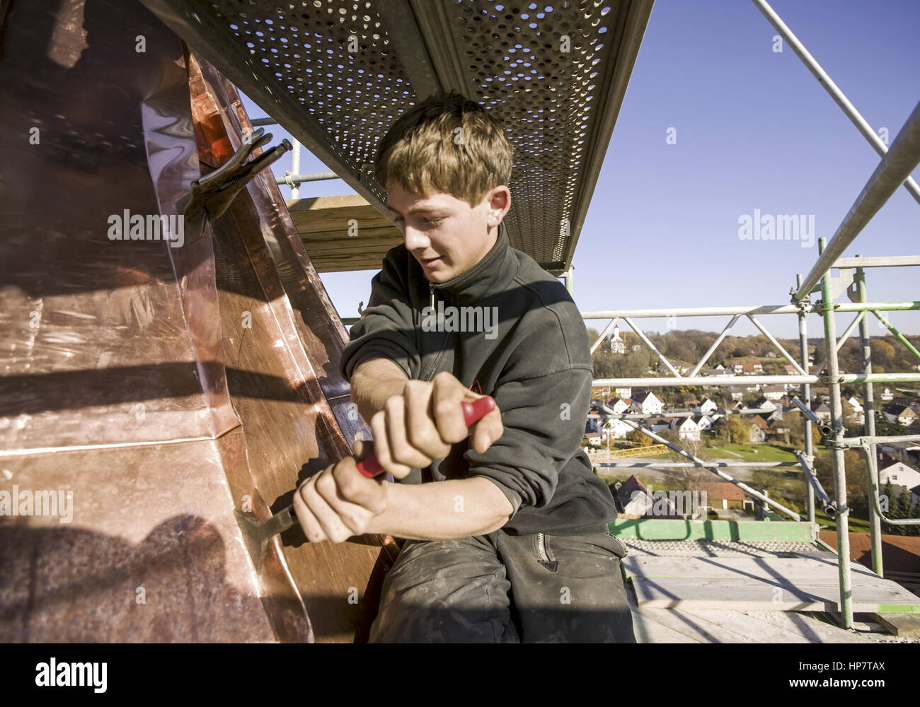 Spengler, Lehrling arbeitet mit Stemmeisen an Kupferdach eines Kirchturms (model-released) Stock Photo