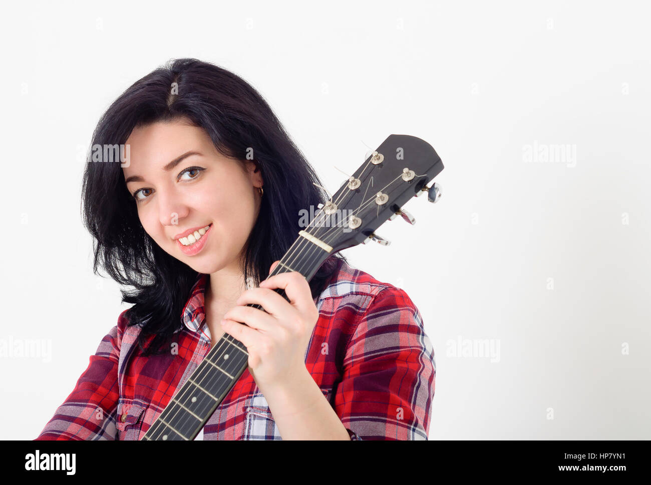 Young cute girl in a checkered shirt holding an acoustic guitar and ...