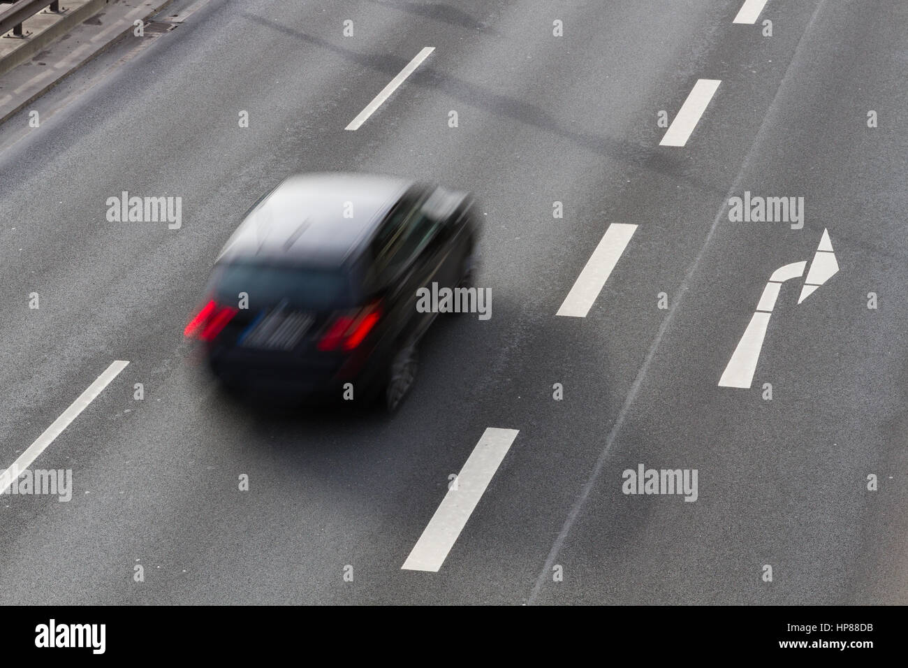 A car driving along a dual carriageway with a right-hand turn filter lane Stock Photo