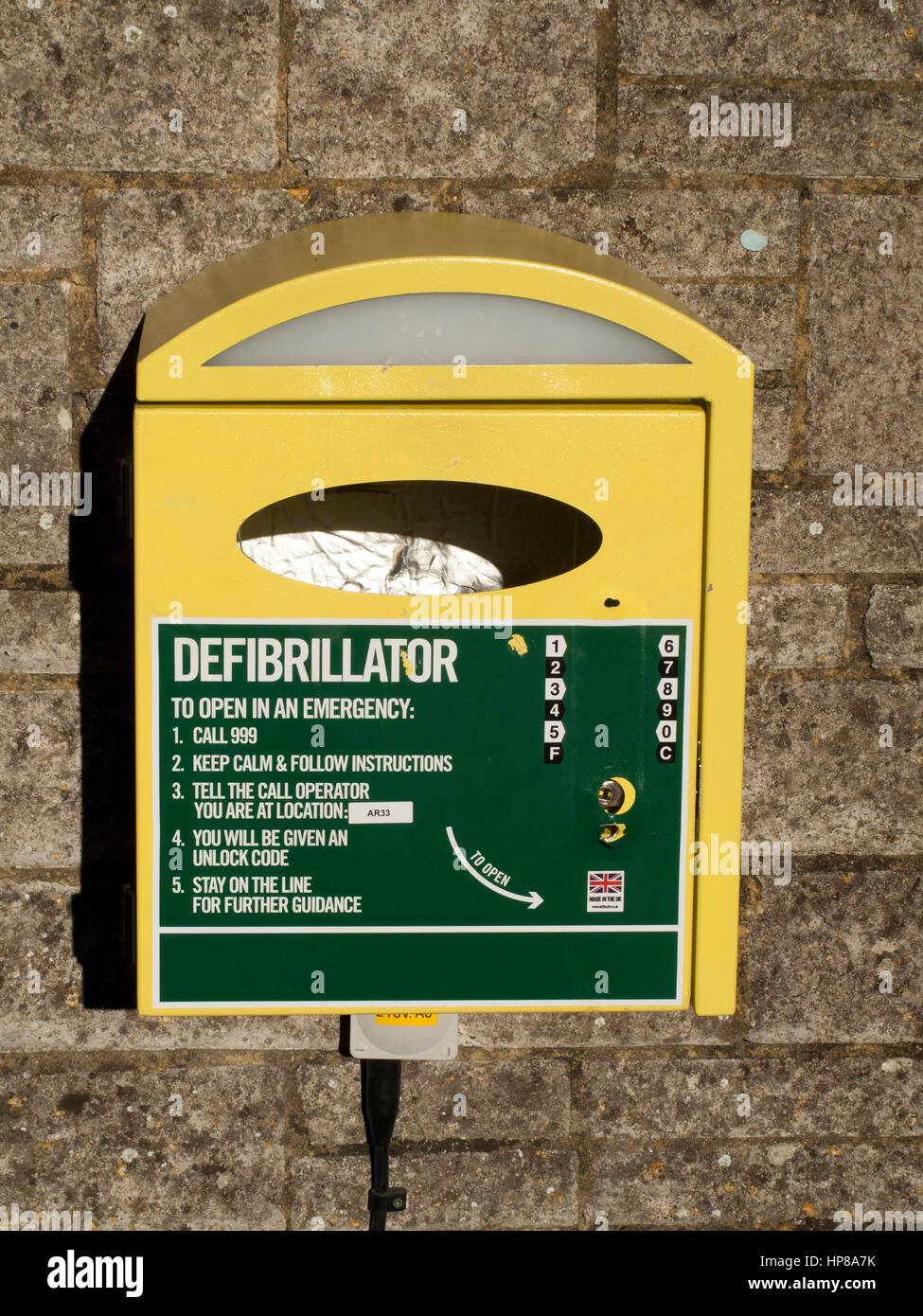 Medical defibrillator mounted on stone wall for use by the general public with instructions Stock Photo