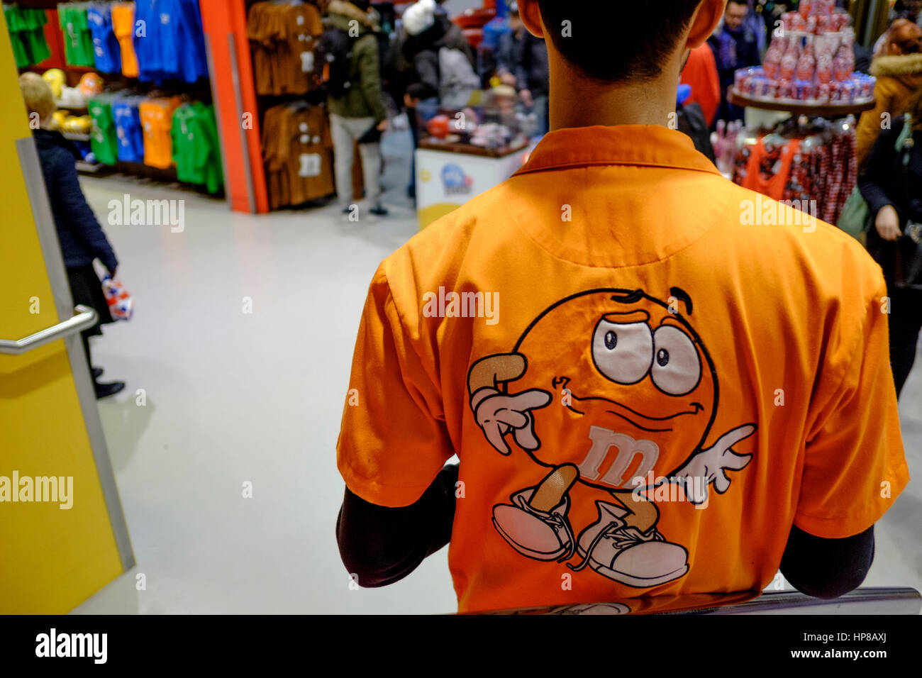 Employee at M&M World store, Leicester Square, London wearing branded company shirt. Stock Photo