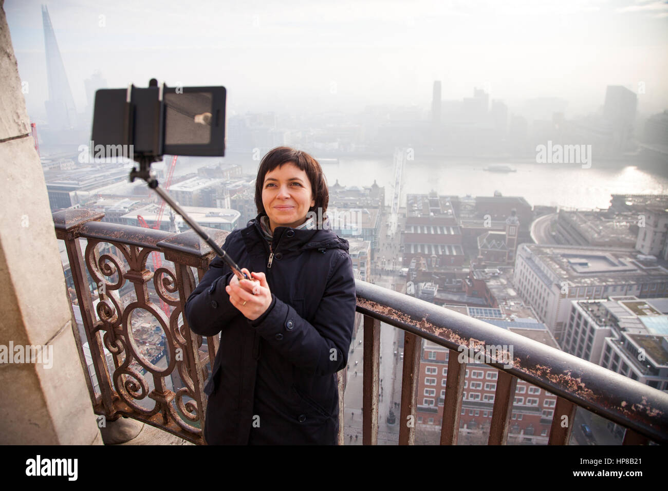 woman taking a selfie from the rooftop of St Paul's Cathedral on a foggy day in London, UK - city break - tourism concept Stock Photo