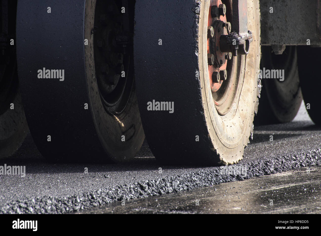 closeup wheel of roller compactor at asphalt road construction site ...