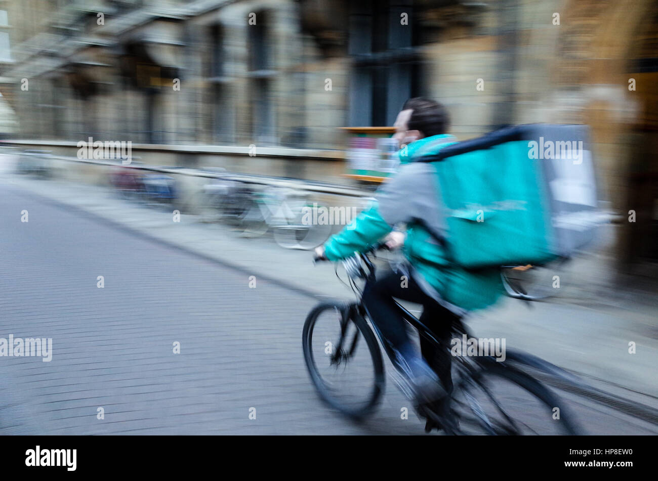 Motion Blur photo of a Deliveroo cyclist rushing through central Cambridge Stock Photo