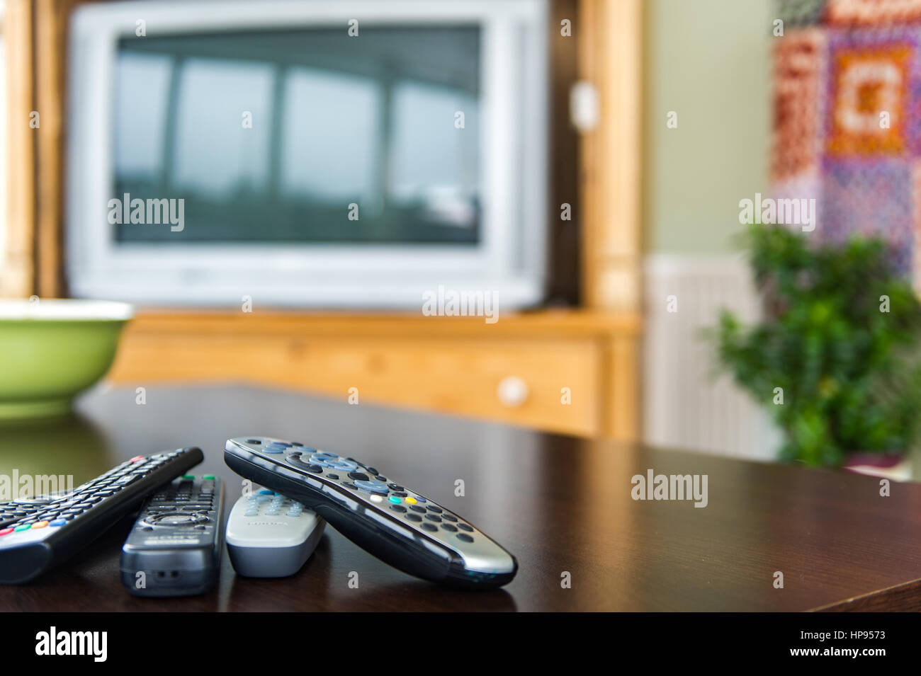 Remote control units on a coffee table in front of a television as a technology concept. Stock Photo