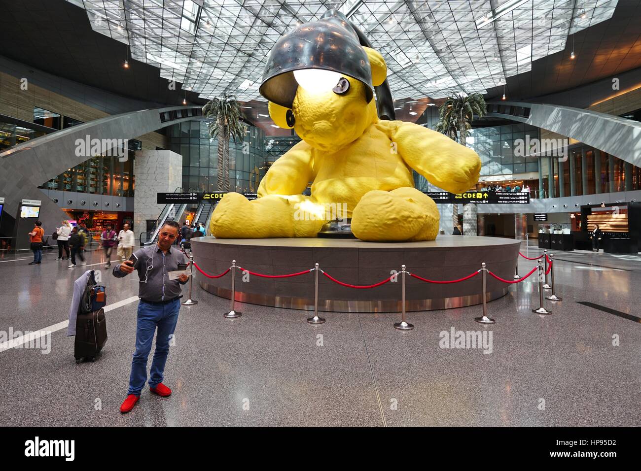 A canary yellow lamp teddy bear sculpture in the middle of the terminal