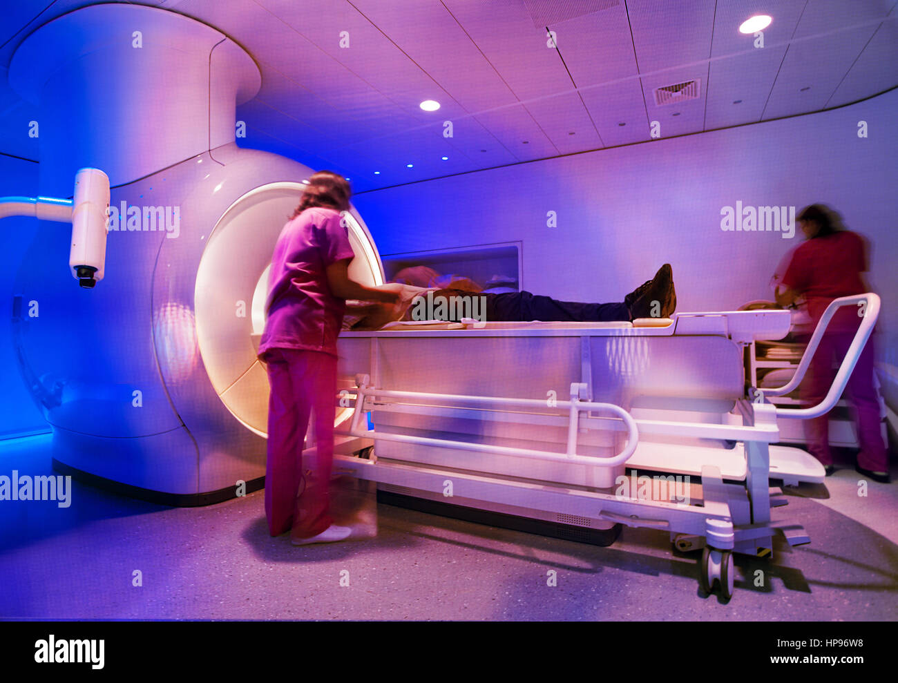 A super powerful modern magnetic resonance scanner is being prepared by nurses for scan with a patient. Stock Photo