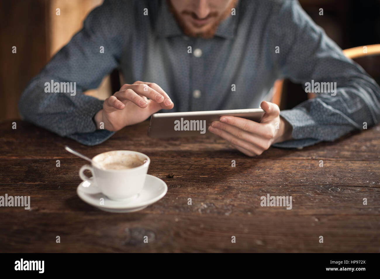 Young man using a digital touch screen tablet on a wooden table, hands ...